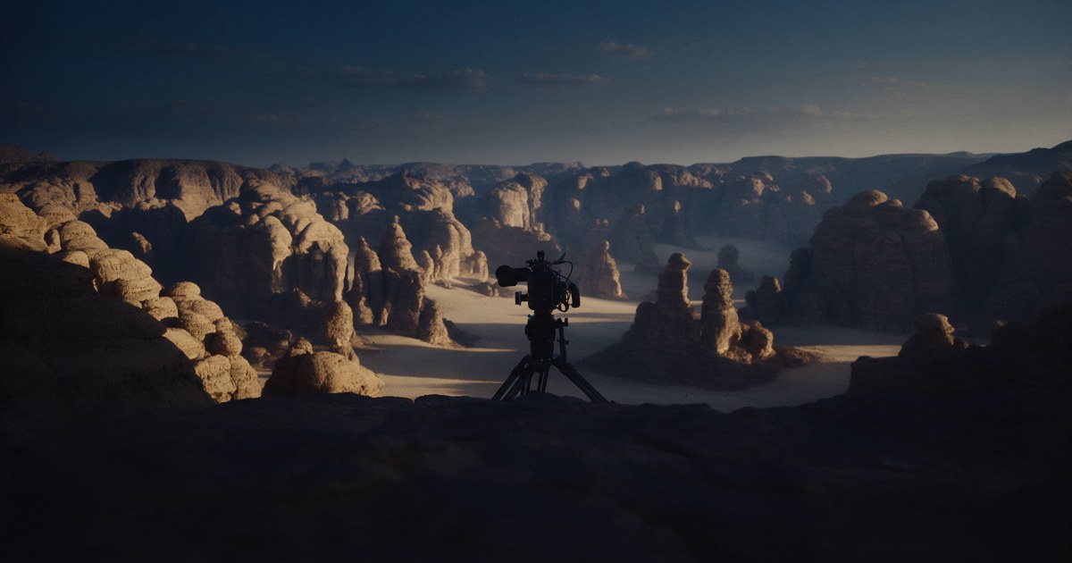 A cinema camera on a tripod overlooking a sandstone desert canyon at golden hour